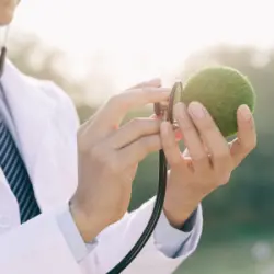 médecin blouse blanche avec stéthoscope écoutant le cœur d'une Terre verte miniature